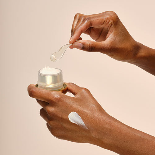 model using spatula to swatch skincare product on hand
